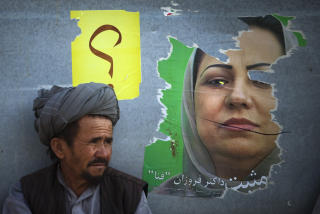 REVET: En afghansk mann sitter ved siden av en revet plakat av en av de to kvinnelige presidentkandidatene foran valget i Afghanistan, Forzan Fana. Hun mener favorittene er kriminelle. Foto: AP Photo/Emilio Morenatti