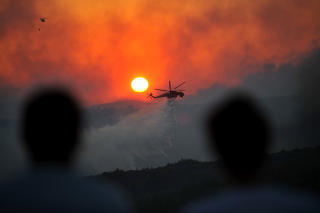  70 KILOMETER NORD:  Et brannhelikopter i aksjon i �sene langs fjellet Kitheronas, 70 kilometer fra Aten.  Foto: AP/SCANPIX.