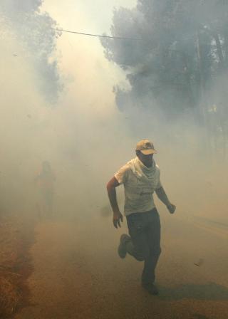  R�MMER:  En mann r�mmer fra r�yken og flammene i Stefanos, 25 kilometer nord�st for Aten. Foto: REUTERS/SCANPIX.