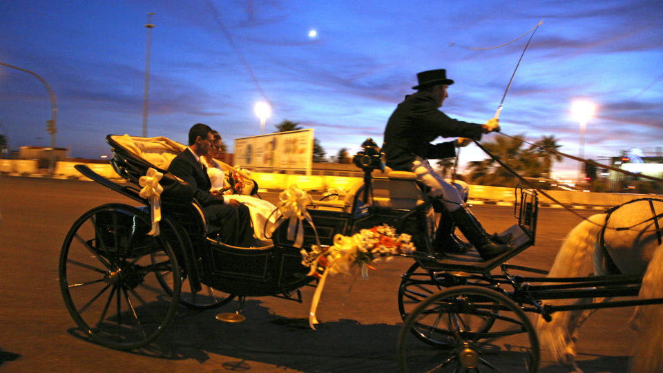 NOSTALGISK: Preget av stundens alvor, sitter den nygifte paret i karljolen mens kusken smeller pisken for � f� de to hvite hestene til � dra avsted etter fotografering ved operaen i Valencia. Alle foto: Eivind Pedersen