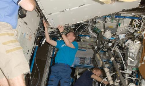 ARBEIDER: Christer Fuglesang (foran) tar bilde av at kollegene Tim Kopra og Kevin Ford  installerer en laboratoriefryser ombord p� ISS. Foto: NASA/EPA/SCANPIX