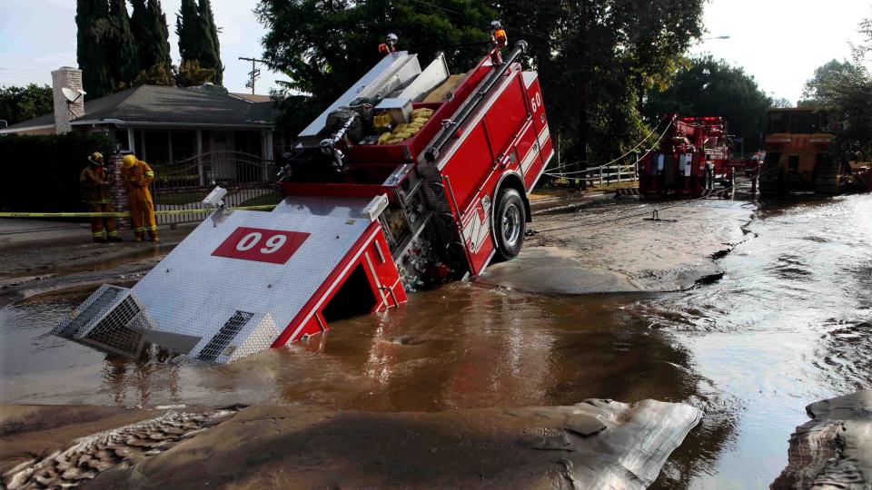 SLUKT: Et plutselig synkehull slukte brannbilen med fire personer om bord i Los Angeles. Brannmennene rakk akkurat � komme seg ut av f�rerhuset f�r det ble fylt av gj�rme. Foto: Scanpix/AP Photo/Nick Ut