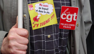 HELSE F�RST: En fransk telekomansatt b�rer et merke som sier Helsa mi p� jobb og i livet... Den tviholder jeg p�!!!. Foto: AFP/NATHALIE MAGNIEZ/SCANPIX