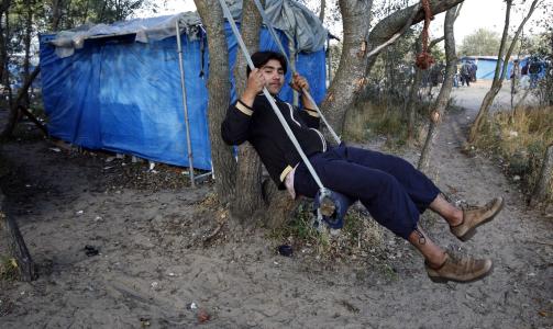 KAN BLI REVET: En afghansk asyls�ker sitter p� en huske utenfor tilholdsstedet sitt i en provisorisk leir som afghanere og andre folk p� flukt har satt opp utenfor havnebyen Calais nordvest i Frankrike. Foto: REUTERS/Pascal Rossignol/Scanpix