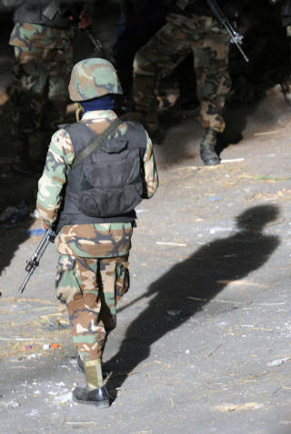 Soldiers walk in front of the Brazilian Embassy in Tegucigalpa, on September 23, 2009. Ousted Honduran President Manuel Zelaya, holed up in Brazil's embassy seeking reinstatement, urged the UN General Assembly Wednesday not to abandon the people of the troubled Central American nation.  AFP PHOTO/Orlando SIERRA