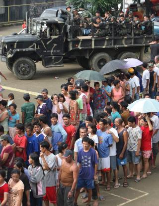 K�: Flomrammede st�r i k� for � f� mat og kl�r. Mange har mistet alt de eier i flommen, og rundt 375 000 personer er i n�dleire. Foto: EPA/ROLEX DELA PENA