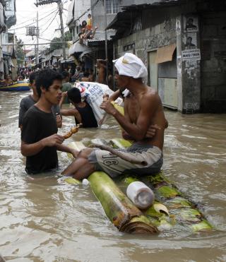 VANN OVERALT: To menn pr�ver � f� i seg litt mat mens flomvannet st�r h�yt i gatene i Binan Laguna, s�r for Manila. Foto: REUTERS/Erik de Castro