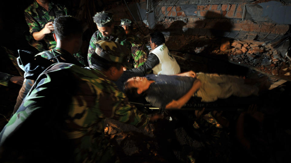 REDDET UT: Indonesiske redningsarbeidere evakuerer her John Lee fra Singapore. I to dager har han v�rt fanget i ruinene av hva som en gang var Maryani International Hotel i Padang. Foto: AFP