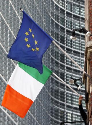 STARTER FEIRINGEN: En mann heiser EU-flagget ved siden av irenes eget flagg. Foto: REUTERS/Francois Lenoir