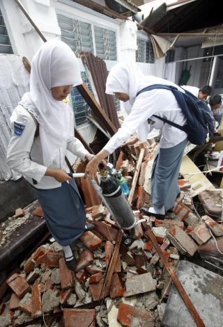 OPPRYDNING: Skolebarna fra byen Padang p� Sumatra m�tte starte skoledagen i dag med � rydde skolebygningen etter jordskjelvet.  Foto: REUTERS/Dadang Tri
