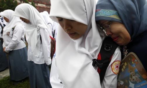 P� SKOLEN IGJEN: Disse indonesiske skolejentene fra byen Padang p� Sumatra er tilbake p� skolen igjen i dag etter det kraftige jordskjelvet som rammet dem forrige onsdag. Her gr�ter elevene og l�reren (til h�yre) mens de ber for ofrene. Foto: REUTERS/Dadang