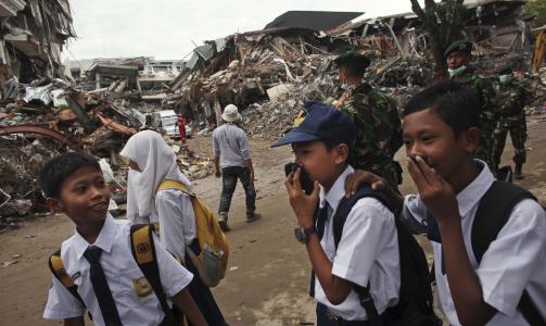 P� SKOLEVEIEN: Indonesiske skoleelever g�r til skolen blant ruinene. Foto: AP Photo/Scanpix