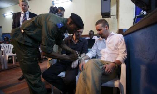 LENKET SAMMEN: Joshua French og Tjostolv Moland har ankommet retten i Kisangani. Her fjerner en rettsbetjent stripsen de var lenket sammen i. Moland og French har etter r�d fra advokat Morten Furuholmen (bak) besluttet � uttale seg i retten, i motsetning til i forrige rettsrunde. Foto: TORE BERGSAKER