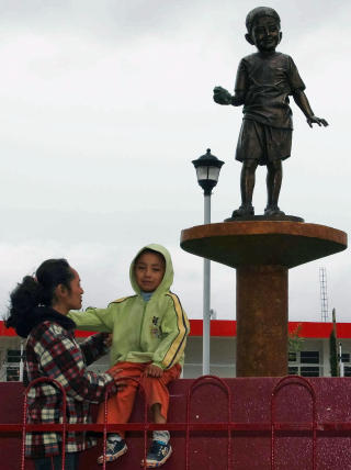 EDGAR FIKK STATUE: Edgar Hernandez  fikk p�vist A H1N1 svineinfluensa i april.  Her er han sammen med moren Maria del Carmen Hernandez foran statuen som er satt opp av ham i La Gloria, Mexico. Foto: AFP/Pablo Spencer
