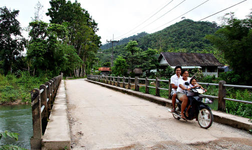 P� LANDSBYGDA: En familie med tre p� en moped smiler gjerne til turister.