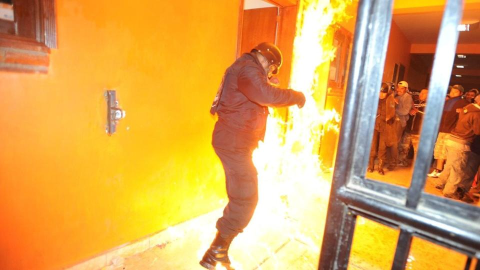 M�TTE REDDE UT KIDNAPPERE: Politiet m�tte redde fire kidnappere som var i ferd med � bli lynsjet av innbyggerne i byen Cujiningo. Denne politimannen pr�ver � slukke flammene etter at kl�rne hans tok fyr. Foto: EPA/LUIS CARBALLO/Scanpix