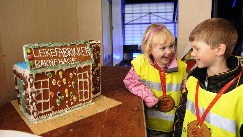 ST�R FORTSATT: Ida Susanne (5) og Robbie (4)  har f�tt hver sin pepperkakemedalje for innsatsen med det fine pepperkakehuset. De to barna fra Lekefabrikken barnehage hadde laget huset sitt f�r Pepperkabebyen ble rasert, men til alt hell hadde de ikke levertdet inn f�r raseringen fant sted natt til s�ndag.
Foto: Marit Hommedal / Scanpix