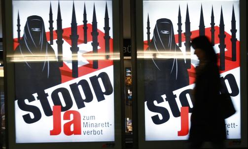 KAMPANJE: En kvinne g�r forbi en av plakatene i Bern som viser kampanjen startet av det nasjonalistiske Sveits folkeparti (SVP)  Foto: Ruben Sprich/REUTERS