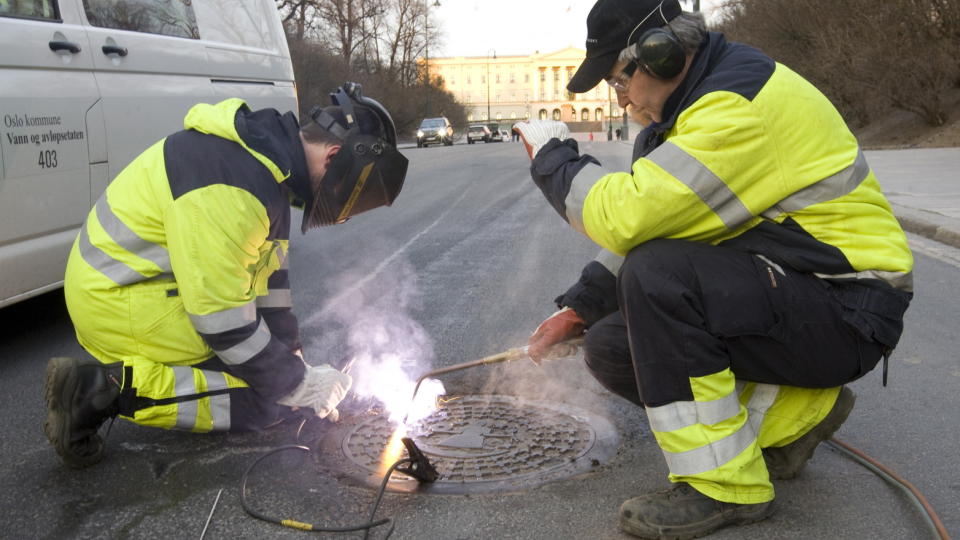 STOR JOBB: Arbeidet med � sikre alle kumlokk i sentrum startet p� Karl Johans gate i Oslo i morges.
Foto: Morten Holm / Scanpix .