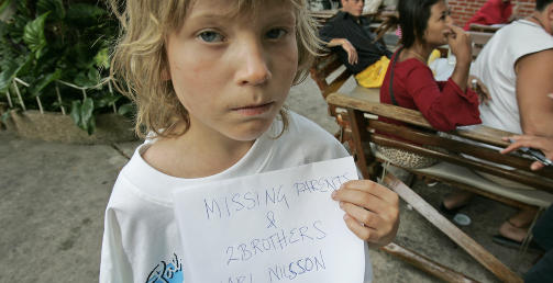 SAVNET FORELDRE OG BROREN: Svenske Karl Nilsson (7) med et skilt som sier foreldrene og broren er savnet, Phuket i romjula 2004. Gutten fra Lule� lekte p� et hotellrom med br�drene Olof, (5), og Vilgot, (3). Foreldrene Thomas og �sa var p� utsiden. Karl overlevde flomb�lgen, og ble funnet p� et buddhisttempel av legen Marie Guldstrand. De andre overlevde ikke tsunamien. Karl ble tatt vare p� av besteforeldrene sine i Sverige, if�lge AP.
Foto: AP /David Longstreath
