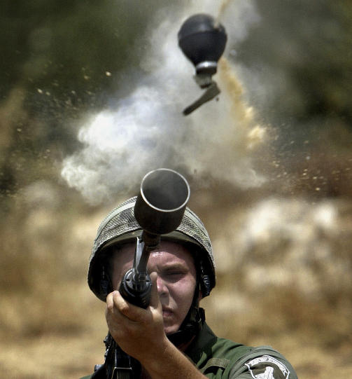 T�REGASS: En israelsk grensevakt avfyrer t�regass mot en palestinsk demonstrasjon mot muren p� Vestbredden. Foto: REUTERS/Goran Tomasevic