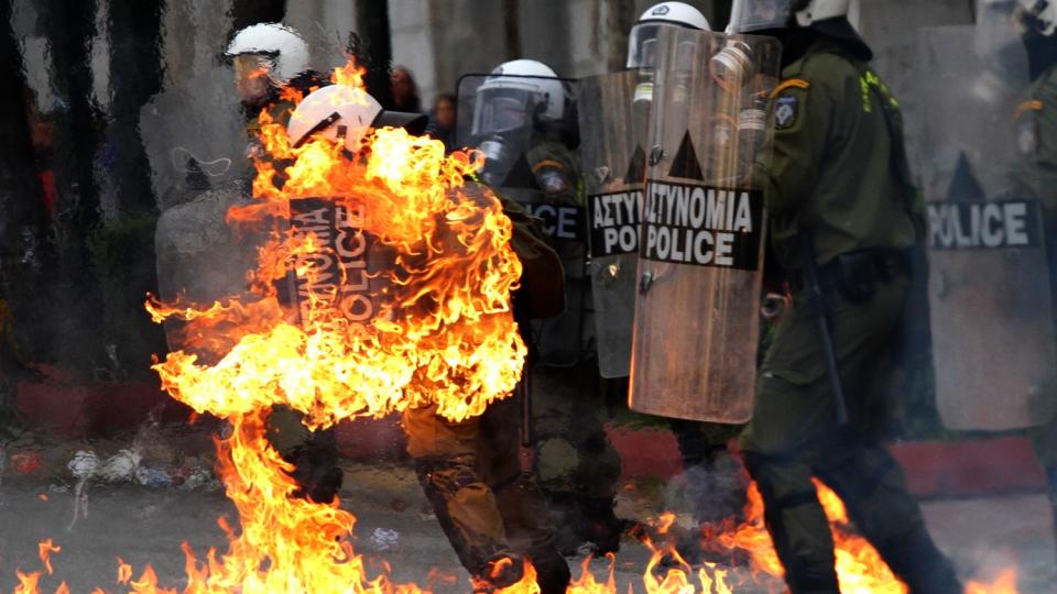 BRANNBOMBE: En politimann tok fyr etter at demonstranter kastet brannbomber mot politistyrkene. Foto: AP photo/Dimitri Messinis/Scanpix