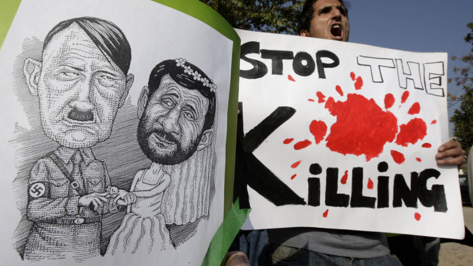 PROTEST: Iranske demonstranter holder et bilde som viser Irans president Mahmoud Ahmadinejad og Hitler under en protest i dag. Demonstrantene protesterte mot manglende sosial og politisk frihet. Foto: AP Photo/Vincent Thian/Scanpix