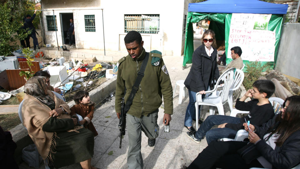BESKYTTER NYBYGGERNE: Israelske politifolk holder oppsyn med det konfiskerte huset. En del av Al-Kurd-familiens eiendeler er plassert i teltet til h�yre. Goto: AFP/Scanpix