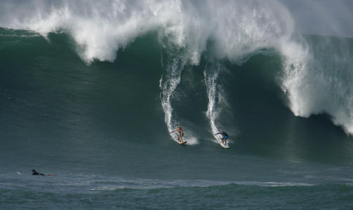 15 METER: To surfere gir seg i kast med en av b�lgene langs norskysten av Oahu. B�lgene ventes � kunne n� en h�yde p� 15 meter, og arrang�rene av konkurransen The Eddie Aikau Big Wave Invitational vurderer � avholde konkurranse i dag. Foto: REUTERS/Hugh Gentry
