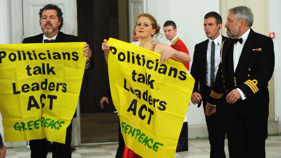 Greenpeace activists unfold a banner distrurbing the arrival of heads of states for the official dinner hosted by Denmark's Queen Margrethe II  in Copenhagen on December 17, 2009 on the 11th day of the COP15 UN Climate Change Conference.     AFP PHOTO POOL/ ERIC FEFERBERG