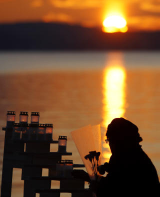 LA NED BLOMSTER: En kvinne legger ned blomster og tenner lys under minneseremonien etter Tsunamien i 2. juledag 2004. Minnestunden ble holdt ved minnesmerket for tsunamien p� Huk p� Bygd�y i Oslo.
Foto: H�kon Mosvold Larsen / Scanpix