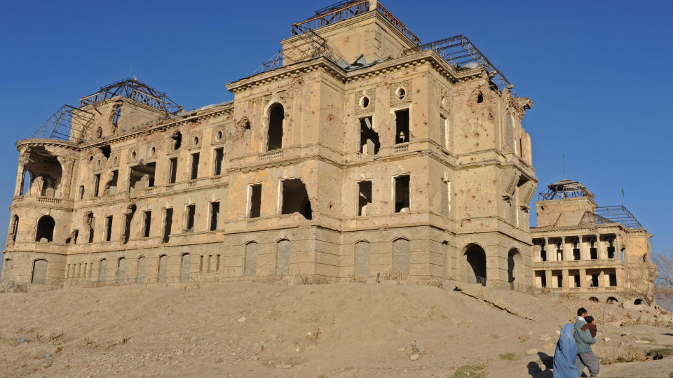 KABUL: En afghansk familie g�r foran et gammelt palass i senter av Kabul. I dette omr�det ble de to franske journalistene kidnappet. Foto: AFP/TAUSEEF MUSTAFA