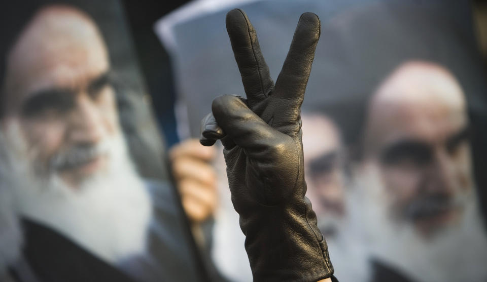 DEMONSTRERER: Reuters og andre utenlandske mediekanaler rammes av irans restriksjoner og muligheten for � ta bilder og filme i Teheran. En person som sympatiserer med regimet laget et Victory-tegn foran et bilde av de iranske politikerne Ayatollah Ruhollah Khomeini og Ayatollah Ali Khamenei under en protest mot oposisjonen i Teheran i g�r. Foto: REUTERS/Morteza Nikoubazl (IRAN - Tags: POLITICS)