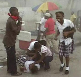 KOLLAPSET: Forbipasserende yter f�rstehjelp en kvinne som falt om p� gata i Port-au-Prince etter det d�delig skjelvet som rammet i g�r kveld, norsk tid. Foto: REUTERS/Reuters TV/Scanpix
