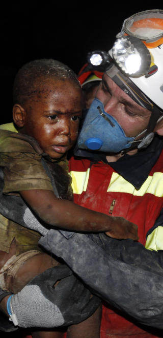 N�D:  En spansk hjelpearbeider b�rer en to �r gammel gutt etter at han ble reddet ut av hjemmet sitt i Port-au-Prince. Foto: AP Photo/Gerald Herbert