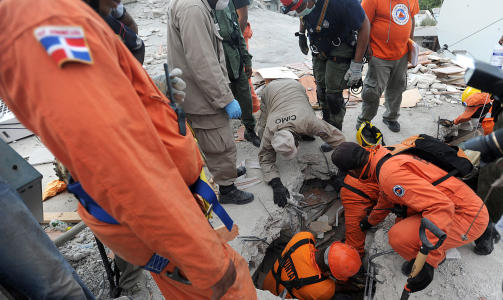 HJELPEN P� VEI: Dominikanske hjelpearbeidere fors�ker � ta seg gjennom sammenraste bygningsmasser. Foto: AFP PHOTO/Juan BARRETO/SCANPIX