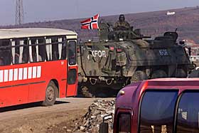 BESKYTTES: I fire �r har norske soldater holdt partene i sjakk utenfor Pristina. Her eskorteres serbere p� vei til jobb i 1999.Foto: Hans Arne Vedlog