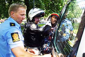 - SKRIV OM DETTE!  Her blir den afrikanske mannen f�rt bort i h�ndjern av politiet. - V�r s� snill og la folk f� vite om dette, b�nnfalt han Dagbladets journalister. 
