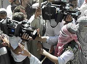 KAMP MOT KAMERAENE: En maskert pakistansk demonstrant fors�ker � skyve bort utenlandsk presse under en pro-taliban-demonstrasjon i Islamabad 28. september.