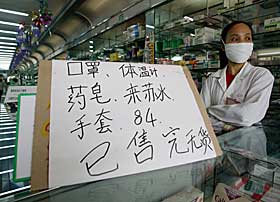 UTSOLGT: En kinesisk ekseditrise ved et supermarked i Beijing st�r foran et skilt som opplyser om at de er utsolgte for ansiktsmasker og munnbind. Tusenvis av kinesere flykter fra den kinesiske hovedstaden i frykt for SARS-viruset.