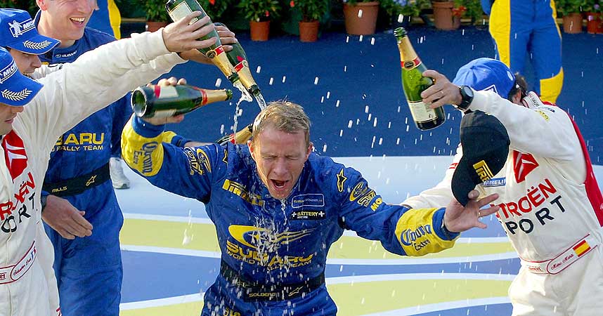  SJAMPIS I ITALIA: Petter Solberg vant Rally Sardinia 2004 . Rivalen S�bastien Loeb (foran t.v.) hjelper ham med de fine dr�pene.