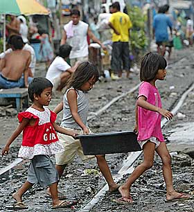 T�FF HVERDAG: Tre filipinske barn b�rer vann ved jernbaneskinnene i et slumomr�de i landets hovedstad Manila.