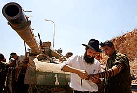 BER FOR ISRAEL: En ultraortodoks j�de ber emd en israelsk soldat n�r den israelske byen Avivim
