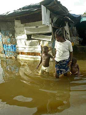 KLIMAENDRINGER: Stigende havniv� vil kunne tvinge store folkemengder til � flytte fra kysten. Flere kommer til � bo tettere og ha mindre � leve av. Denne kvinnen i Liberia forlater det flomrammede huset sitt sammen med barna i september i �r.