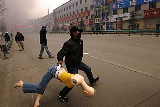 RAMPONERTE BUTIKKER: En tibetaner b�rer med seg en utstillingsdukke fra en butikk. Rasende demonstranter knuste vinduer og brant ned butikklokaler eid av hankinesere.