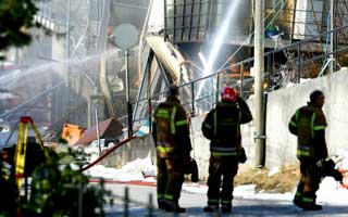 BRENNER FORTSATT: Klokka 12 i dag brant det fortsatt i den sammenraste bygningen i �lesund.