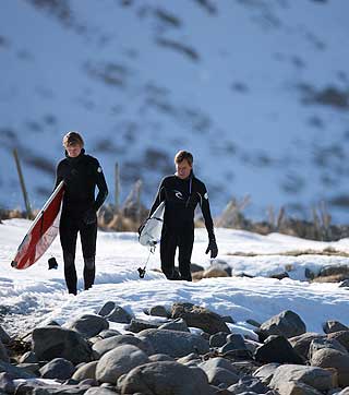 V�TDRAKT MED VARMEELEMENTER: Lokale Tommy Olsen som driver camping og surfutleie og Tom Curren p� vei ut i vannet.