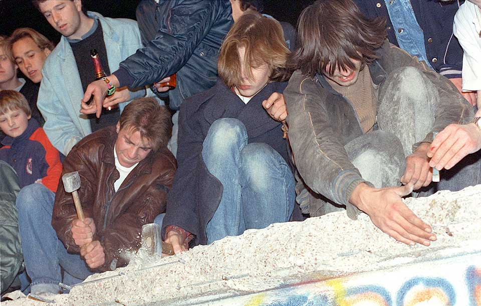 TOK SAKEN I EGNE HENDER: 10. november 1989 klatret �sttyskere opp p� muren og startet � hakke den i stykker med enkle verkt�y. Ett �r senere ble store bulldosere satt inn i arbeidet med � fjerne muren for godt.