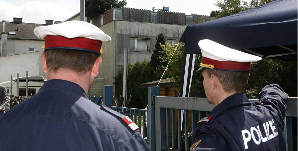 Politiet: To politimenn holder vakt utenfor huset til Josef Fritzl. Huset har ogs� blitt kalt 