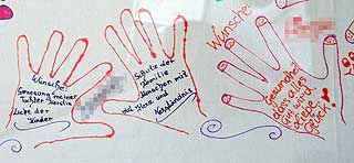 TEGNEDE HENDER: Inne i omrissene av hender har familien skrevet ned �nsker og h�p. Tegningene henger p� torget i Amstetten.